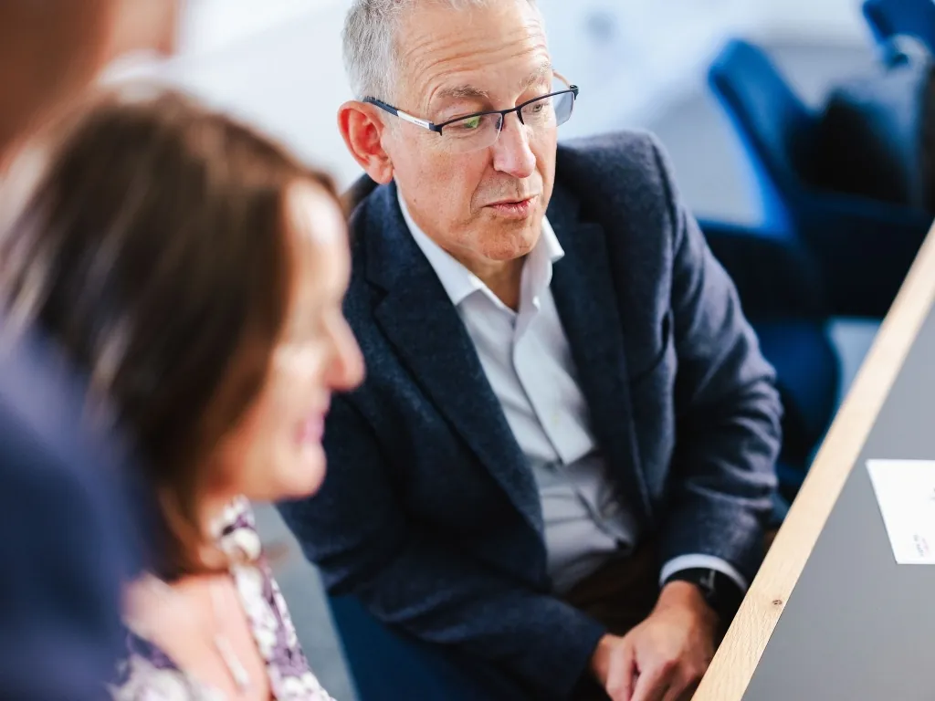 A male financial expert in glasses focusing on a document during a strategic business review.