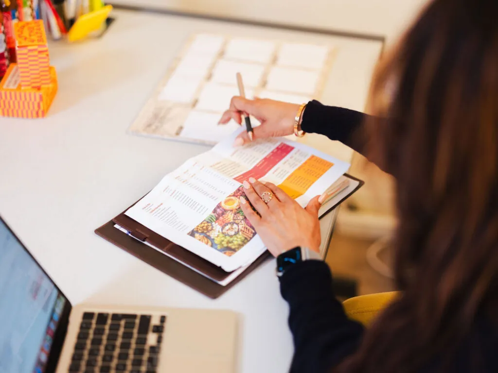 female financial advisor looking at a printed spreadsheet in a folder with laptop in foreground